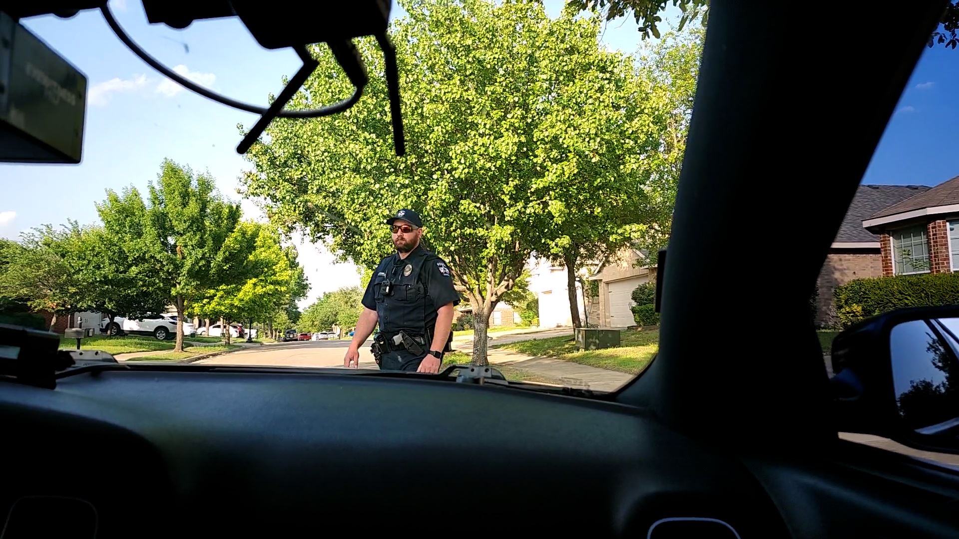 Officer Johnson waves to passing car standing in front of police car