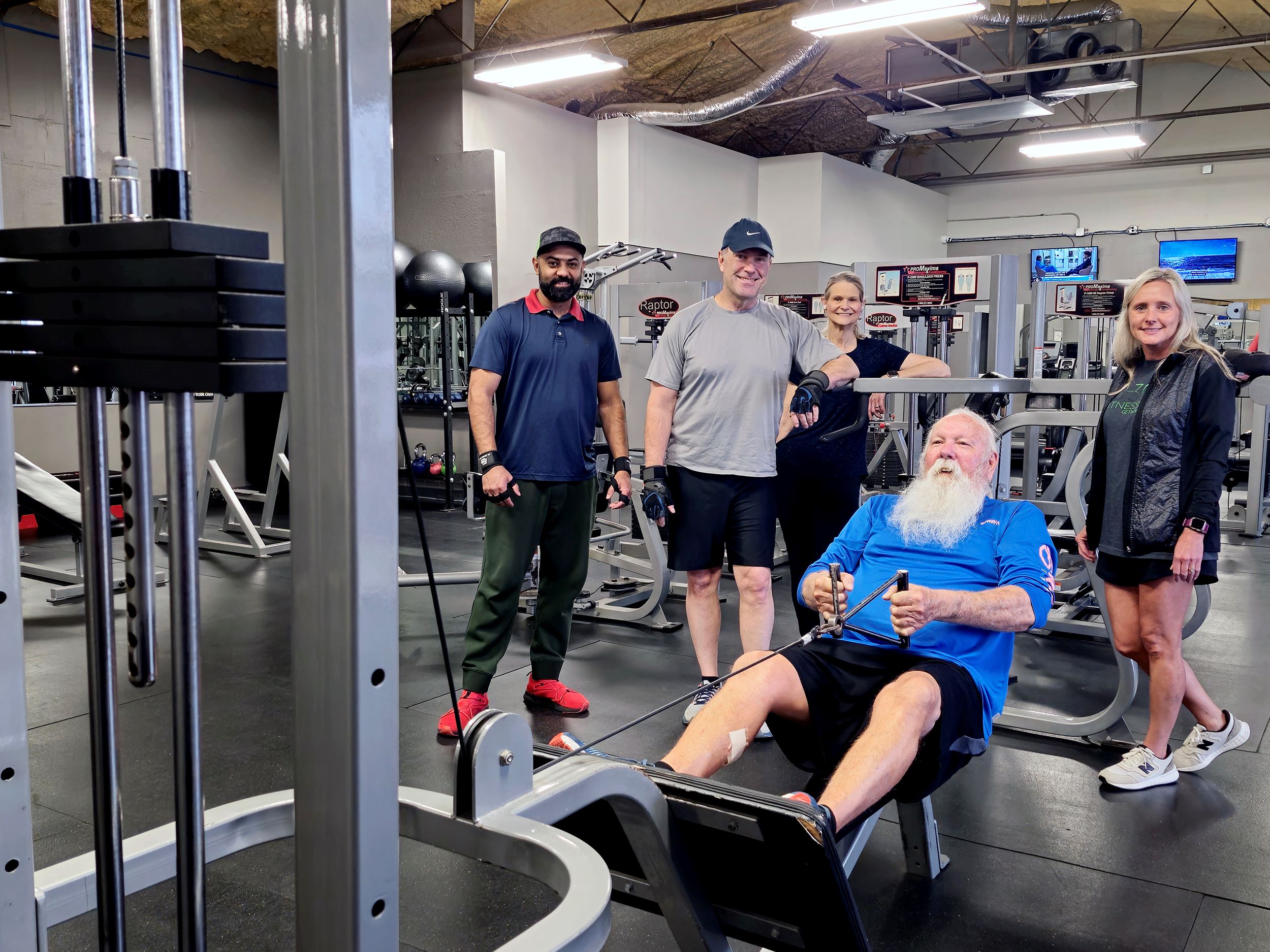 Men and women standing near exercise equipment smiling at camera