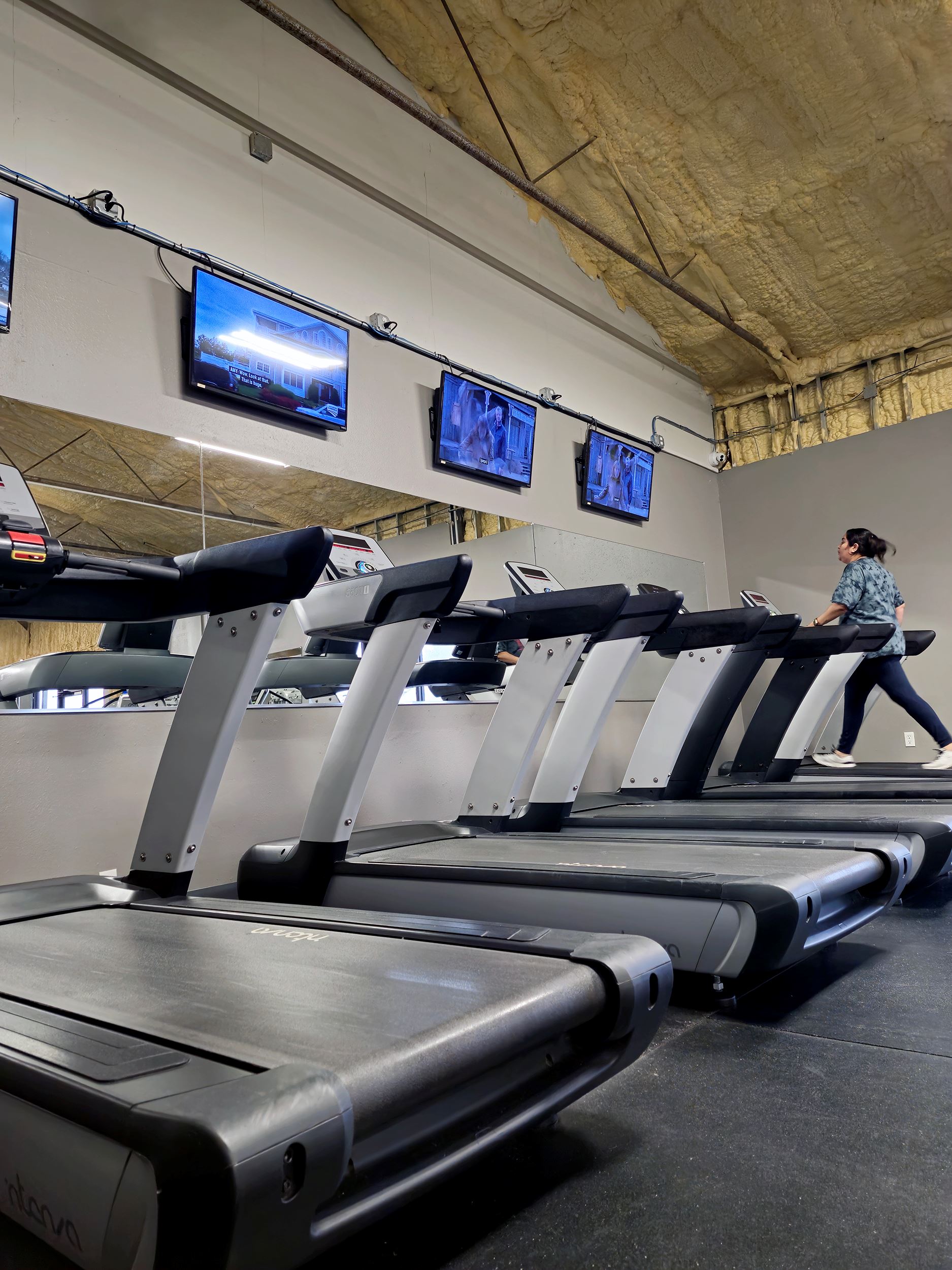 Treadmills lined up in front of mirror