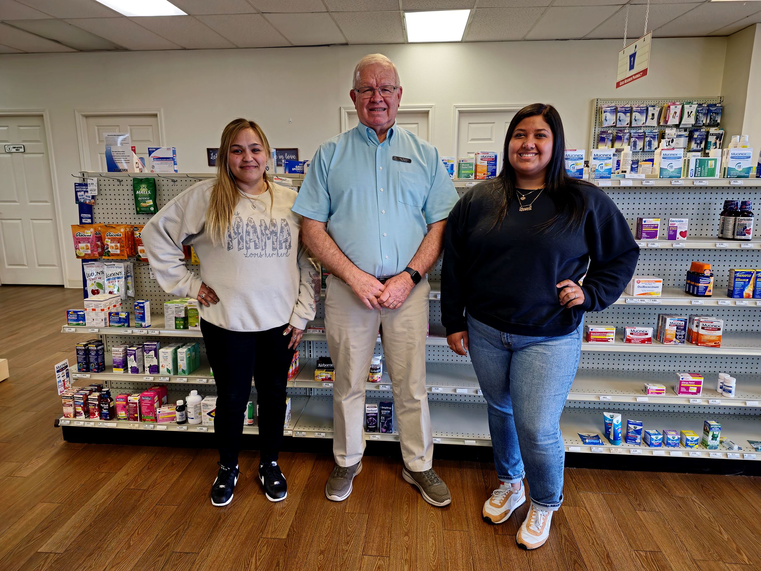 Gary Mayberry poses with staff members in front of shelves of medicine