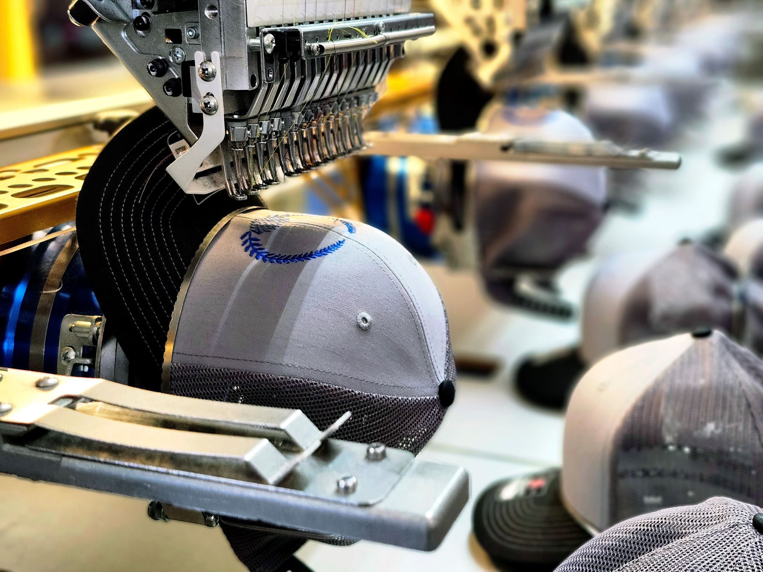Close up view of an embroidery machine with a hat being embroidered
