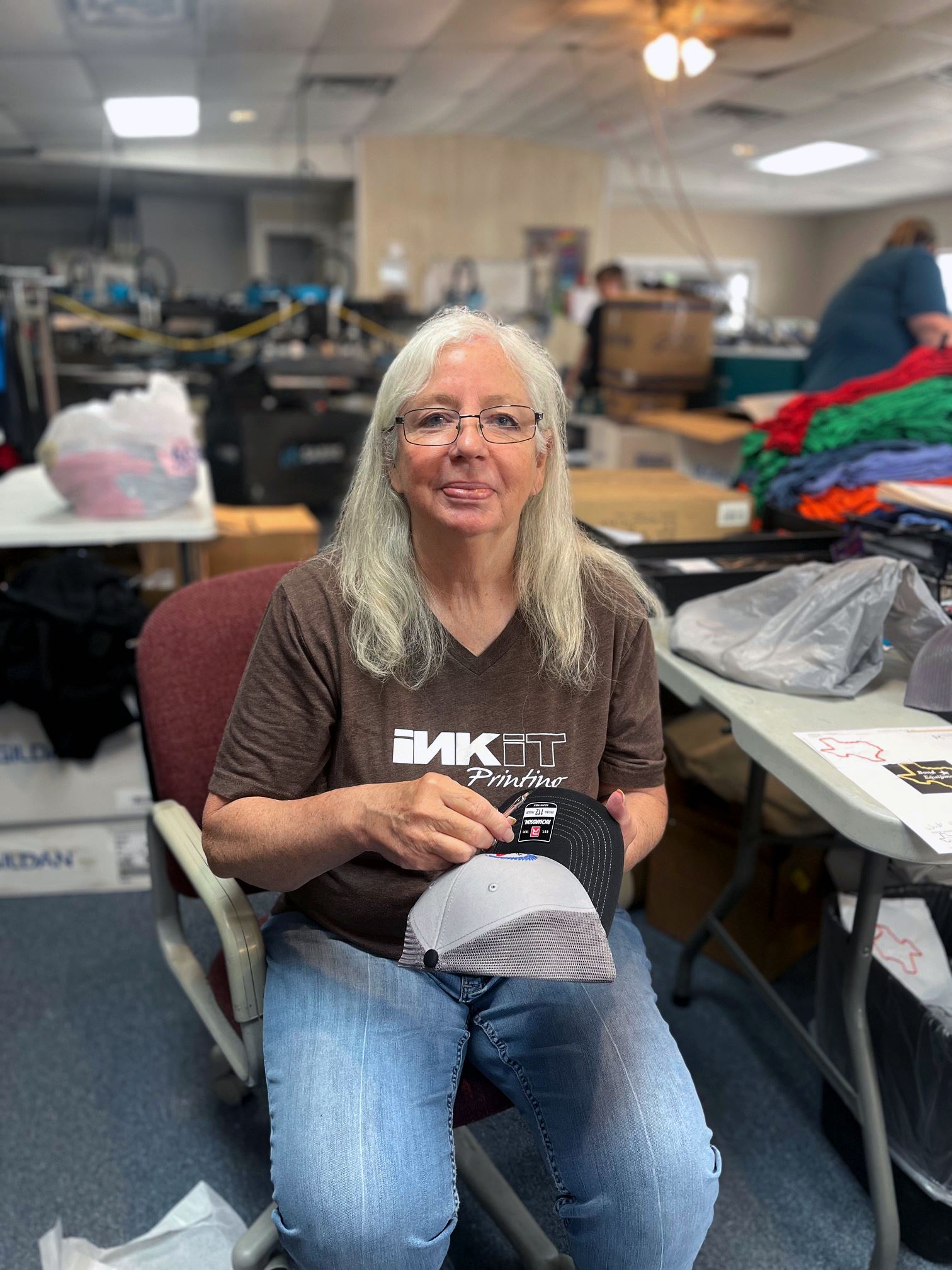 Woman sitting down weeding a cap after embroidery