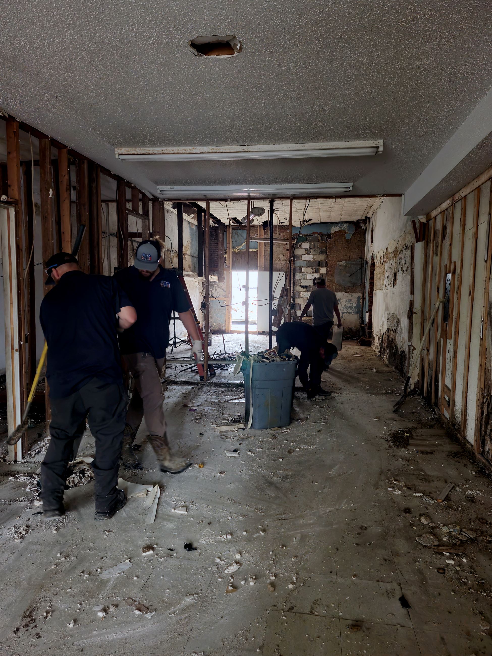 Public Works employees strip walls at an old building
