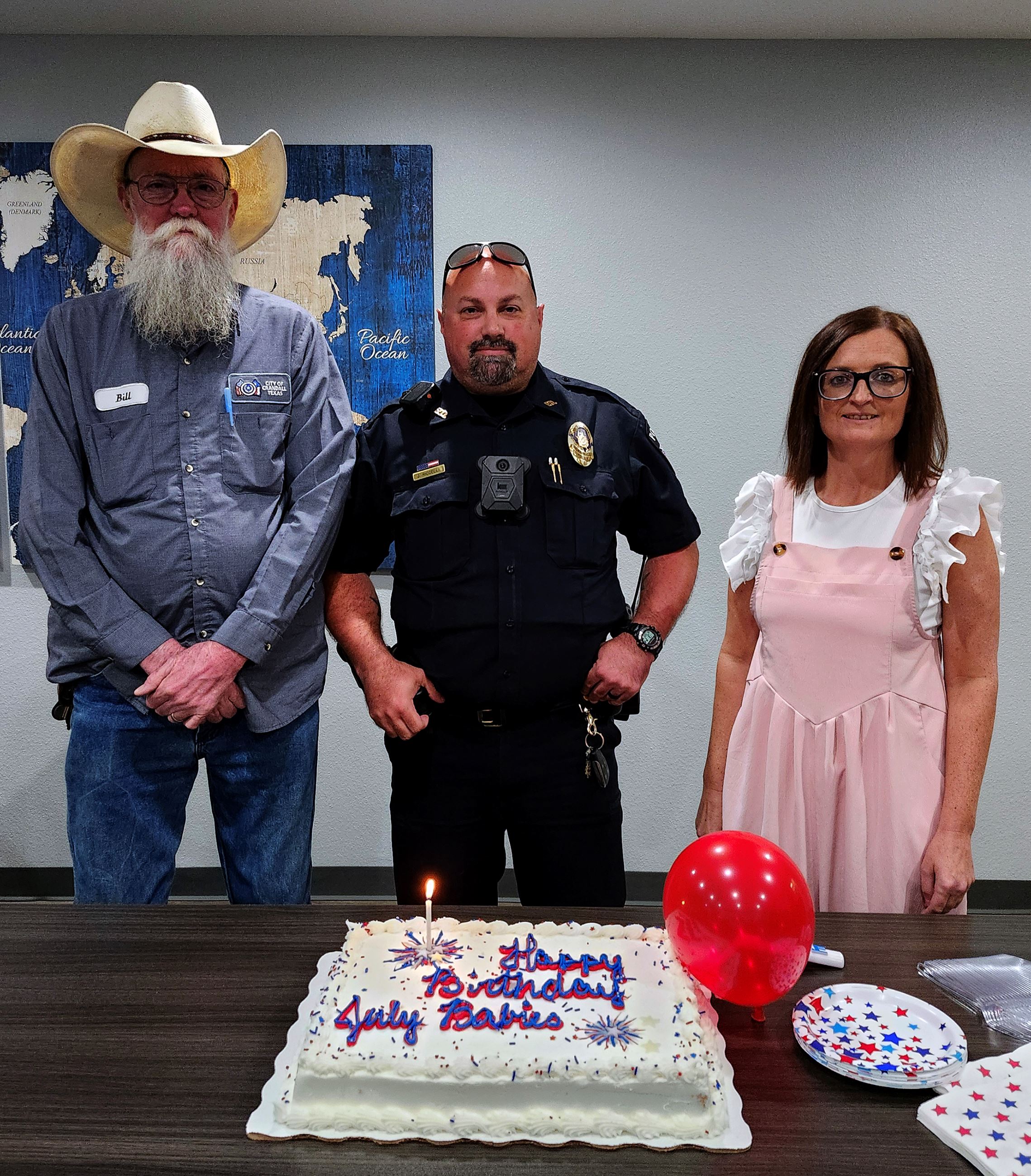 Staff members pose in front of cake if their birthdays fell in July